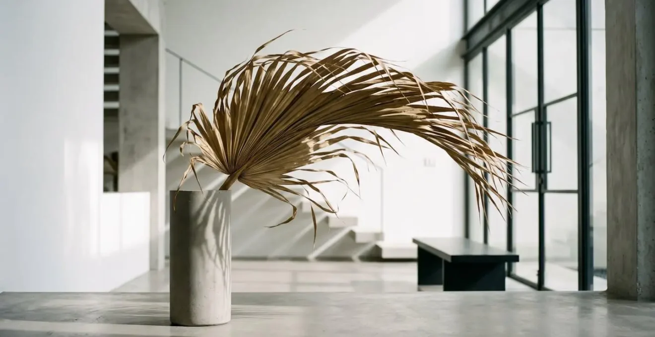 Single dramatic dried palm fan in minimalist vase against modern geometric interior showcasing organic asymmetry
