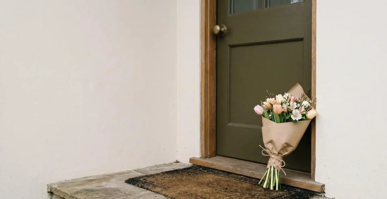 Wide shot of a simple flower bouquet placed on a residential doorstep capturing the anticipation of an unexpected romantic gesture