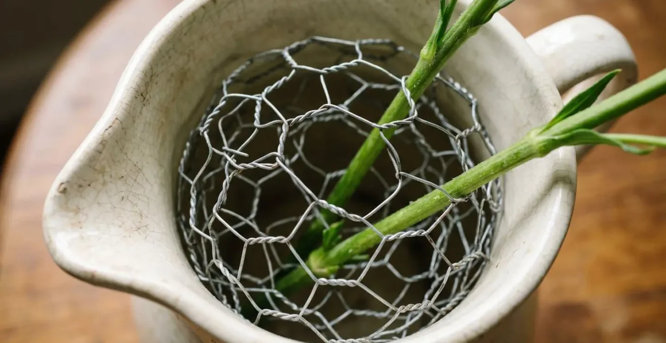 Close-up macro detail of chicken wire floral frog inside vintage ceramic pitcher for flower arrangement support